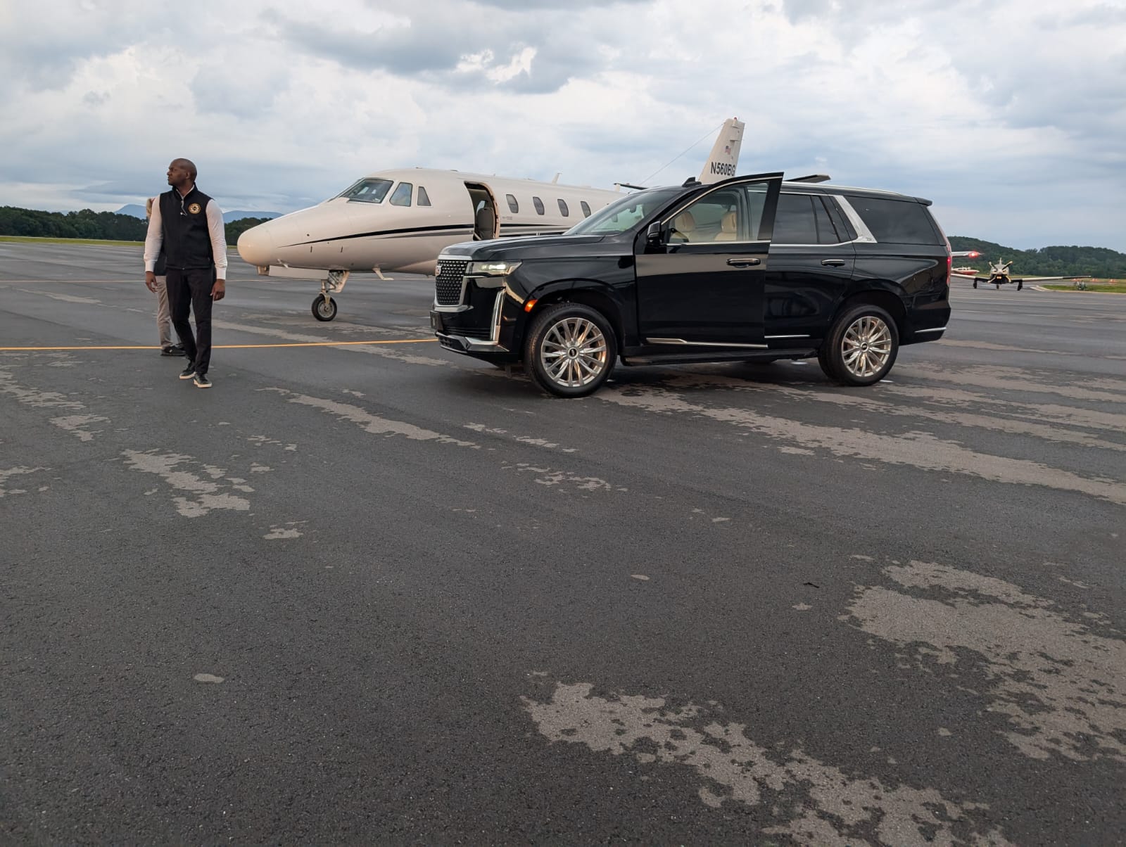 A Hawque protection professional conducting a tarmac advance beside a private aircraft and secure vehicle.